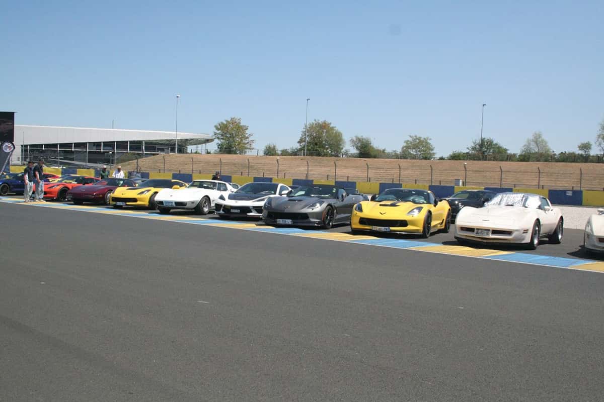 Douzaine de Chevrolet Corvette toutes générations alignées sur la grille du circuit Bugatti.
