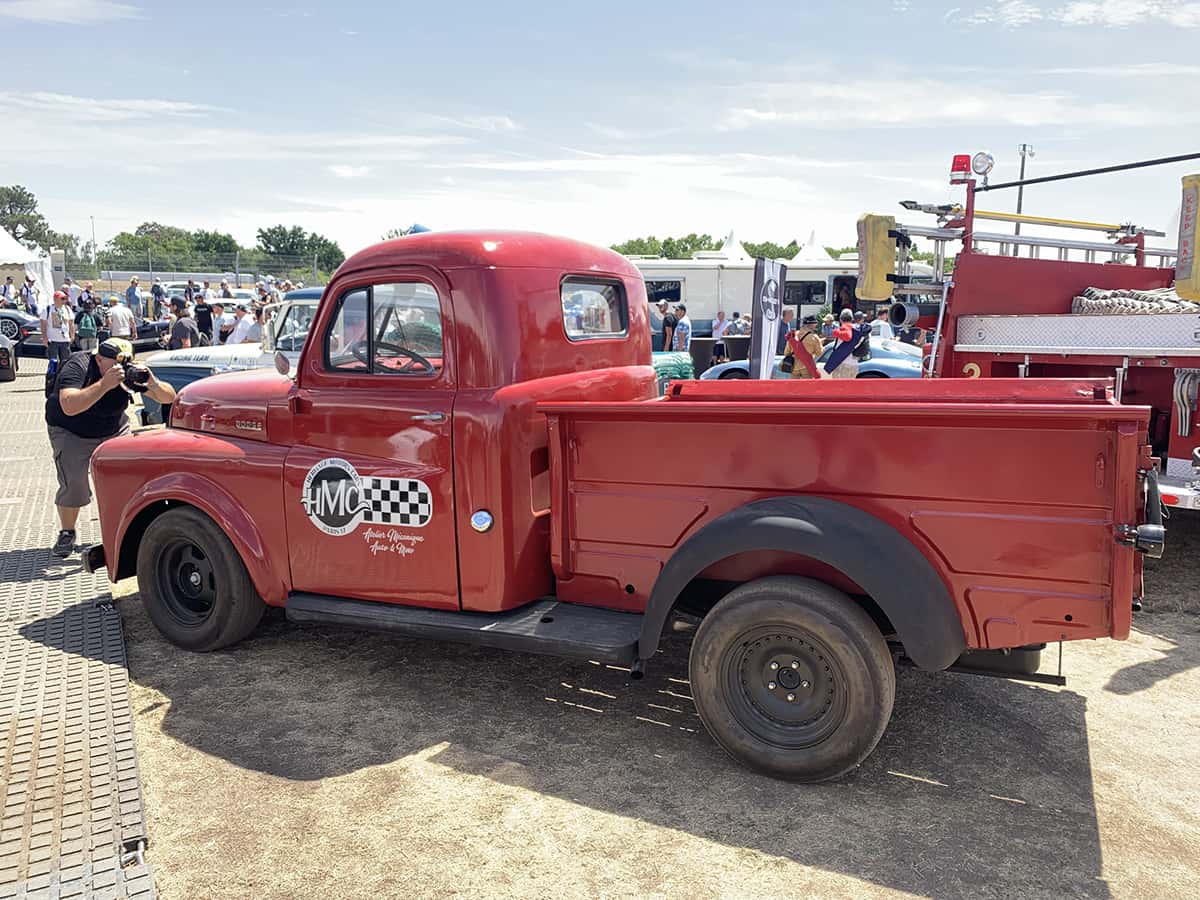 	Pickup Dodge rouge siglé HMC servant de logistique dans le paddock du Mans Classic 2025.