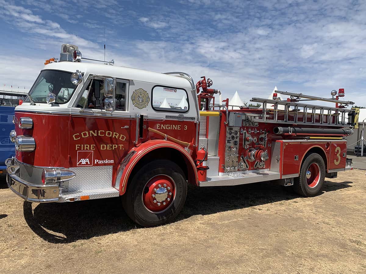 Ancien camion‑pompe Concord Fire Dept rouge, chrome rutilant, exposé au village Mans Classic 2025.