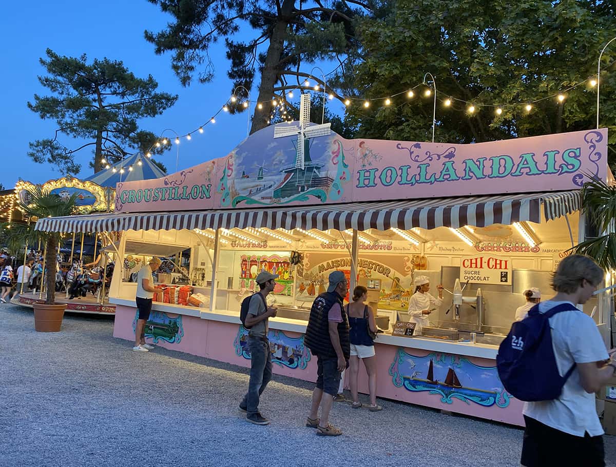 Stand croustillons hollandais illuminé, douceurs et glaces sous guirlandes lumineuses.