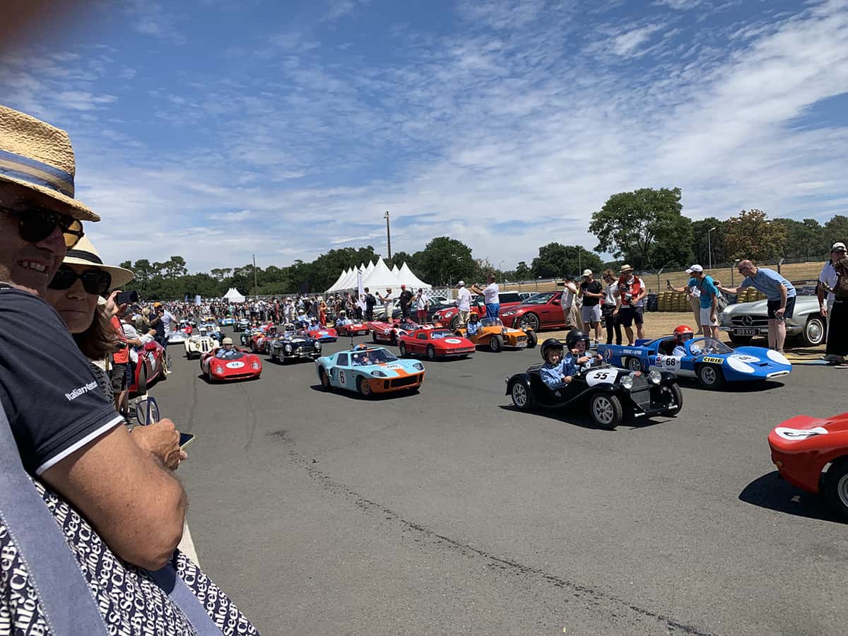 Parade Little Big Mans : enfants pilotant répliques miniatures sur le circuit Bugatti, foule de spectateurs.