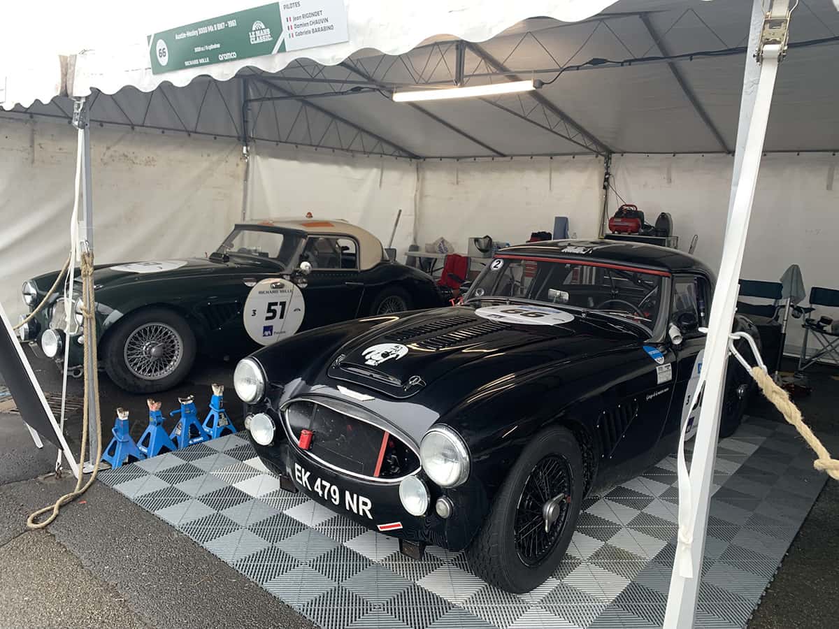 Prototypes bleus Alpine/René Bonnet alignés sous bâche, sol détrempé, Mans Classic 2025.