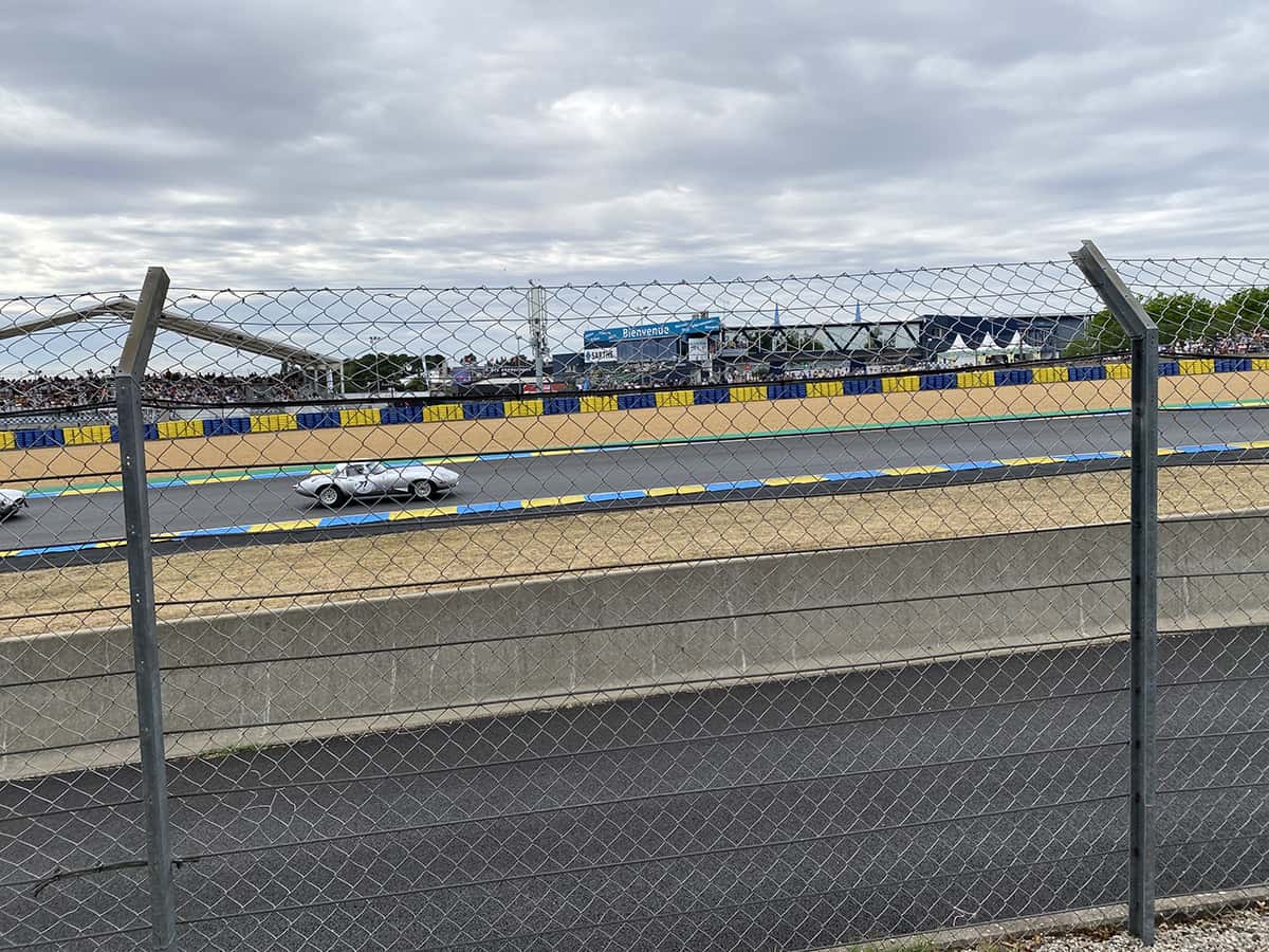 Jaguar Type E argent filant sous la passerelle Dunlop devant tribunes pleines, Mans Classic 2025.