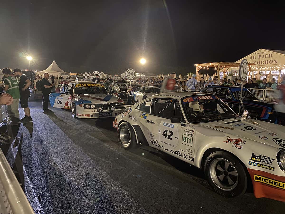 Porsche 911 RSR #42 et BMW 3.0 CSL #06 alignées sous les projecteurs, grille de nuit Mans Classic 2025.