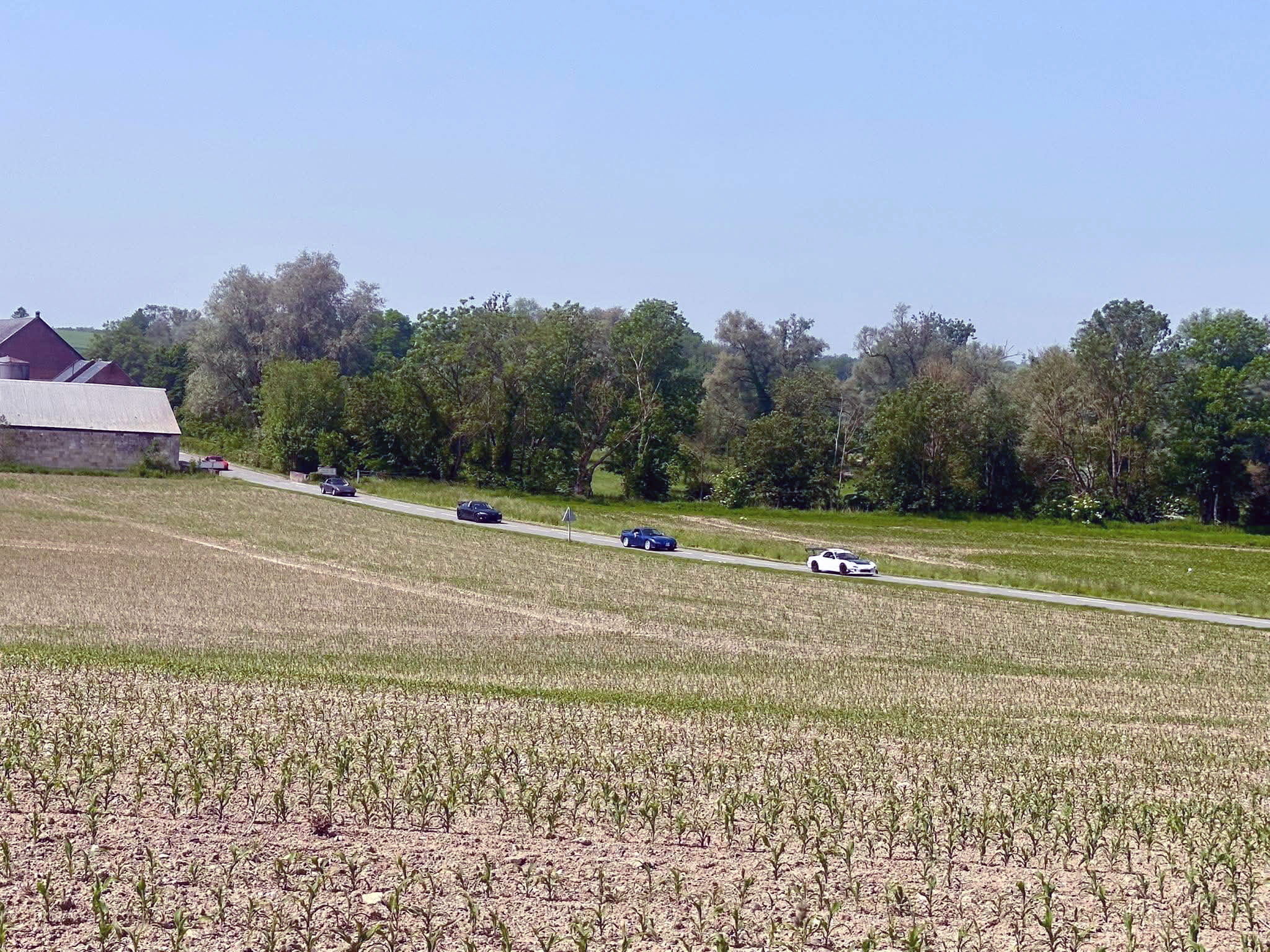Convoi du Classic Rotary Day dans les plaines agricoles de l'Aisne Convoi de véhicules à moteur rotatif Wankel traversant les champs de l'Aisne lors du Classic Rotary Day - vue panoramique sur la campagne picarde avec plusieurs voitures dont une Mazda RX-7 blanche