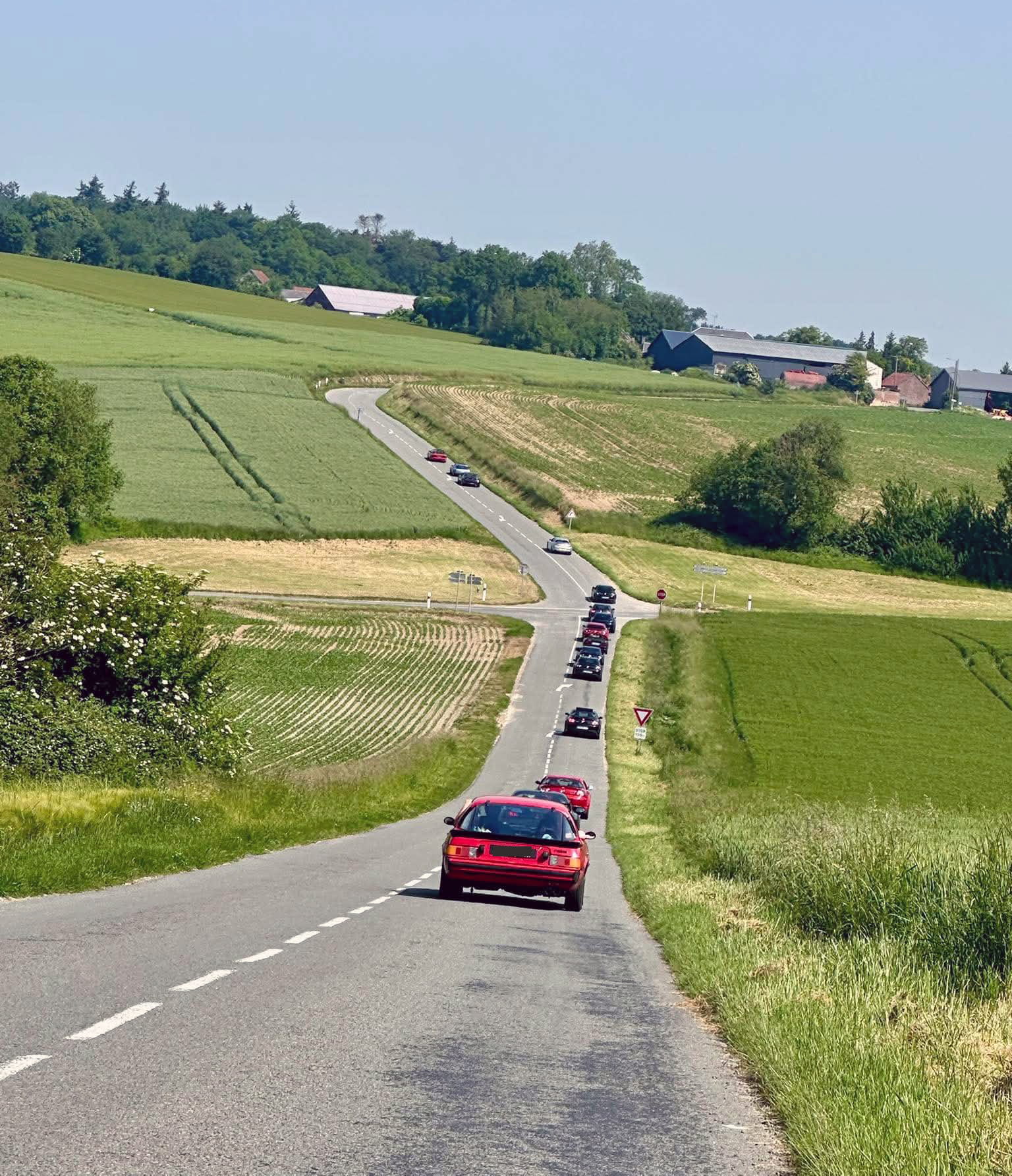Premier trajet du Classic Rotary Day à travers les plaines de l'Aisne Convoi de véhicules à moteur rotatif Wankel sur une route de campagne dans les plaines de l'Aisne lors du Classic Rotary Day - vue arrière d'une Mazda RX-8 rouge en tête de convoi