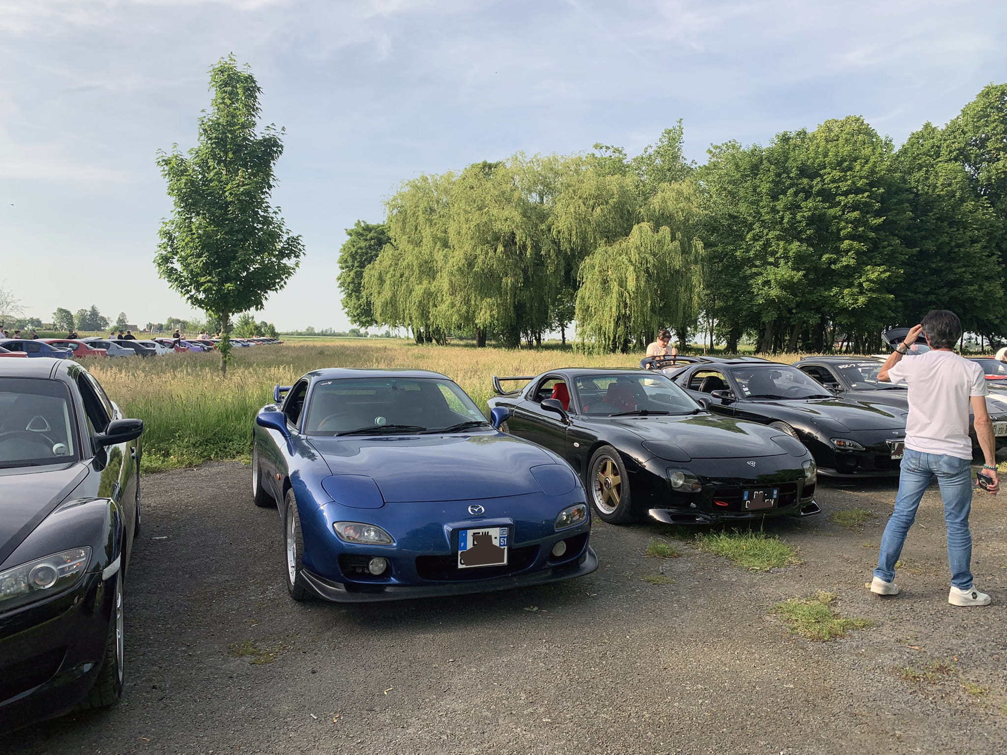 Classic Rotary Day 2026 - les RX-7 FD3S dont la bleue de Jimmy sur l'aérodrome de Niergnies Rangée de Mazda RX-7 FD3S sur l'aérodrome de Niergnies lors du Classic Rotary Day 2026 - FD bleue de Jimmy de 1999 au premier plan, suivie de plusieurs FD noires, RX-8 noire à gauche en transition vers la lignée moderne